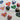 handpainted wooden heart pendants with various floral designs laying on a sketchbook with ideas for the pendants drawn