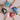 Eight heart-shaped pendants with gold chains. The pendants are painted with various designs in blue, pink, green, red, and white. Each pendant has a pearl or gold bead on the pendant.